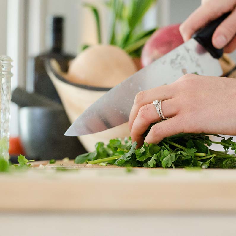 Woman cutting fresh herbs with kitchen knife